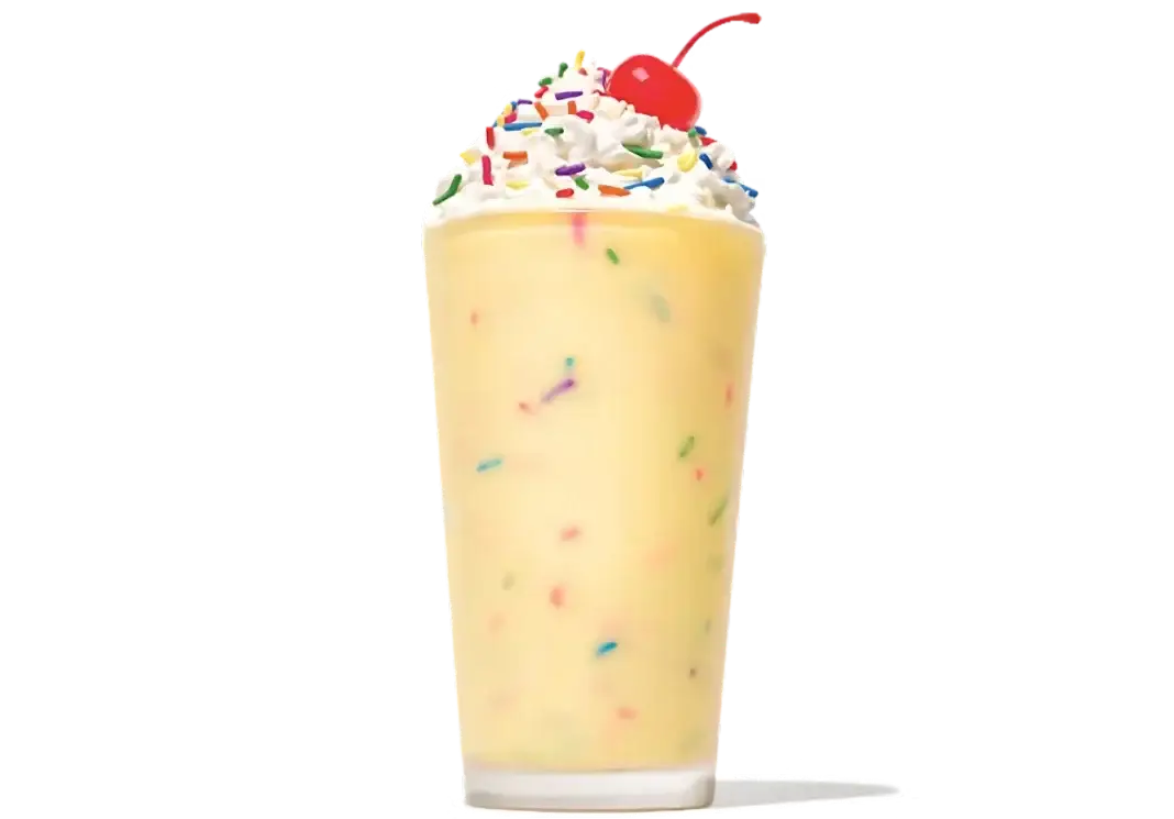 Creamy Birthday Cake Milkshake topped with whipped cream and colorful sprinkles in a tall glass