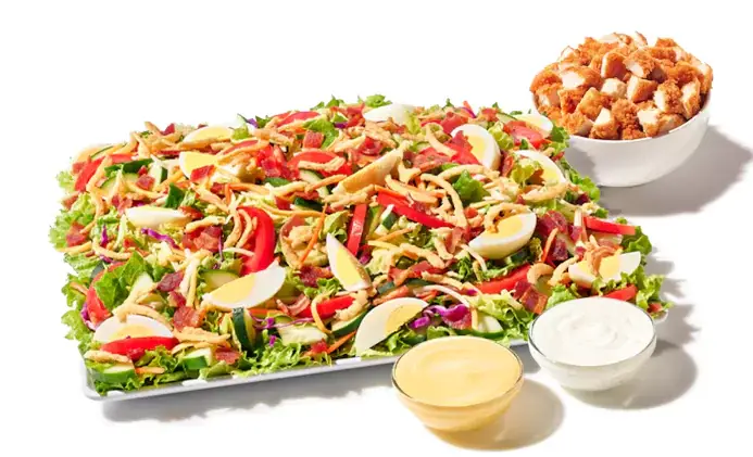 Cobb salad platter with chicken, eggs, bacon, tomatoes, cheese, avocado, greens, Texas toast, and dressing