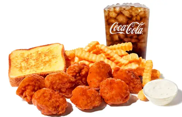 Plate of eight boneless chicken wings with golden fries and a beverage cup on the side.