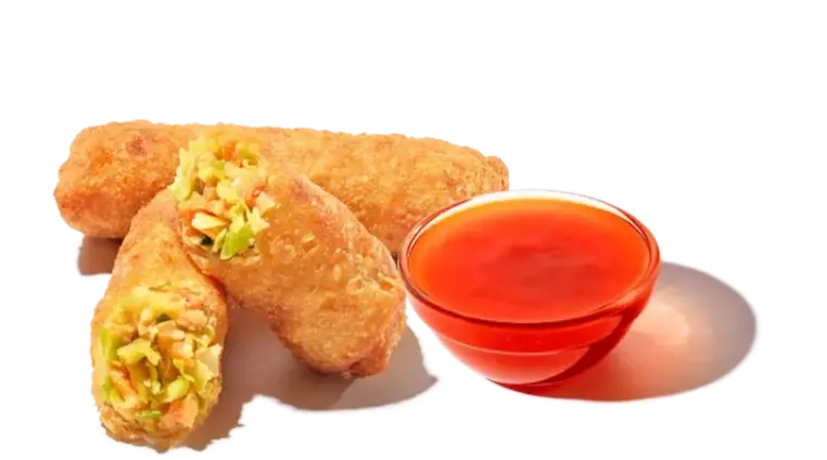 Golden-brown crispy veggie egg rolls filled with fresh vegetables and cabbage on a white plate