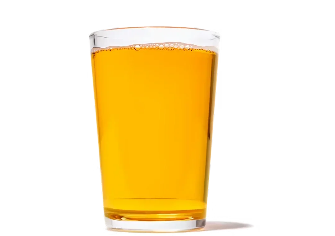 Tall, clear glass filled with a golden/amber beverage (like apple juice or beer) with a thin layer of foam on top.